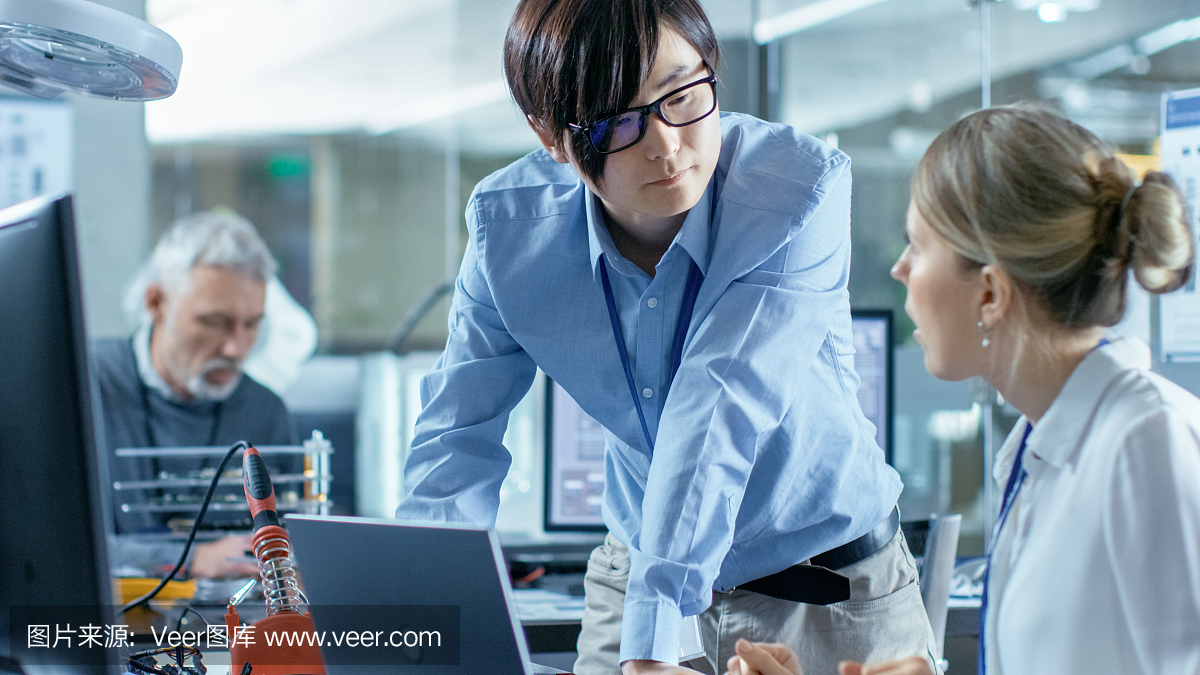 女計算機科學家用綠色屏幕模型連接電路板到她的筆記本電腦。她在先進技術實驗室工作。